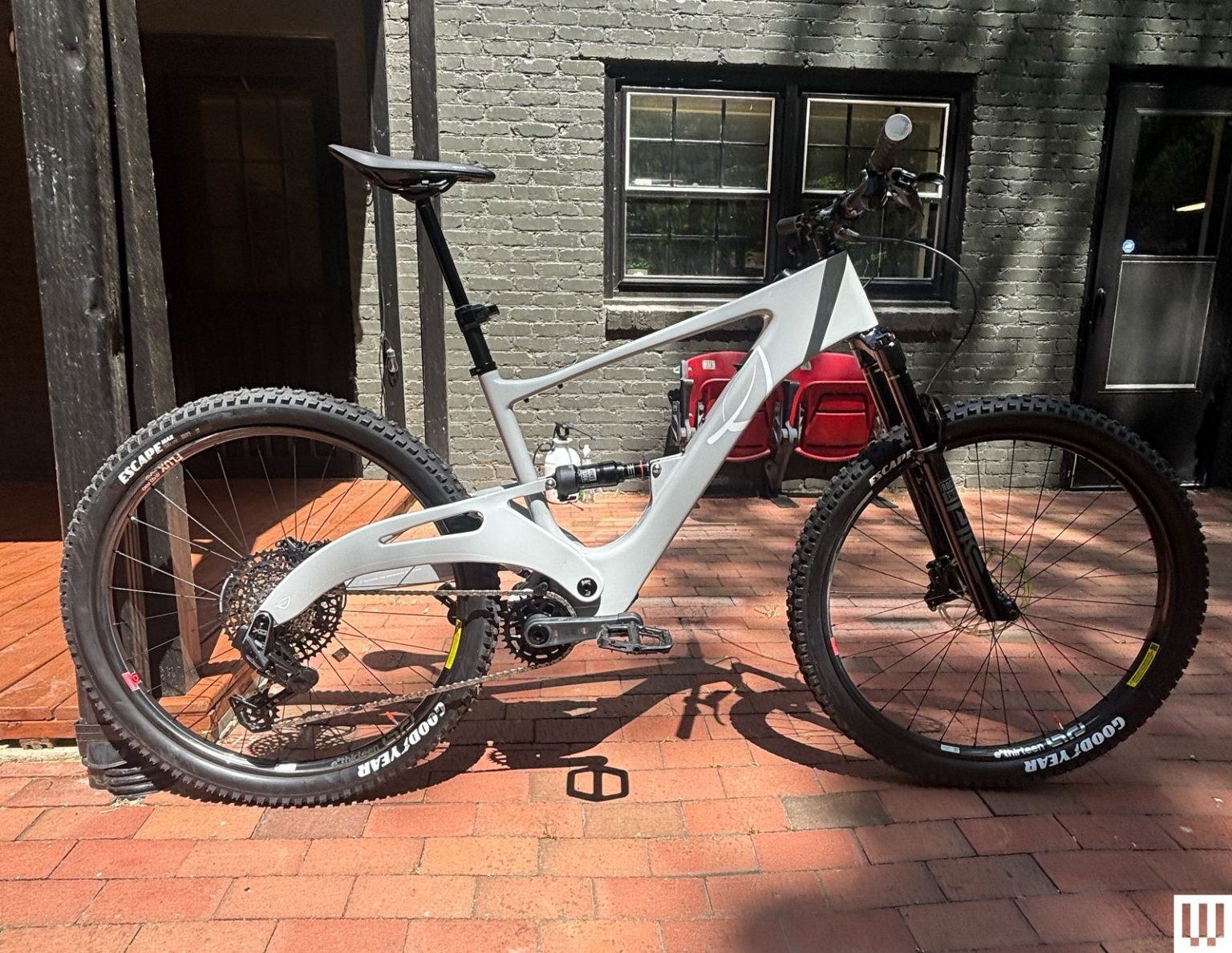 Lauf eElja Electric Mountain Bike Review: Power Trip Side view of a black and white electric mountain bike parked on a paved sidewalk with a grey residential building in the...